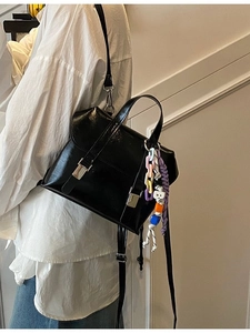 Chic black glossy leather bucket bag with silver buckles and colorful chain charm
