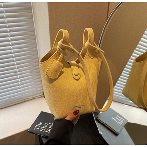 Detail showing high-quality yellow leather bucket bag with pebble texture and adjustable strap