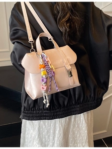 Pale pink crossbody bucket bag with glossy finish and colorful alphabet bead charms