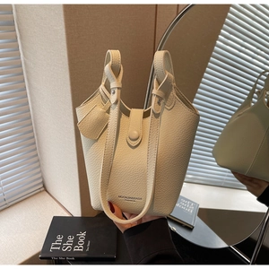 Detail of cream leather bucket bag featuring a unique knotted handle and drawstring closure