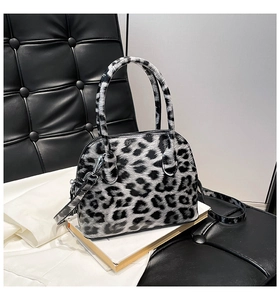Detail of leopard print handbag featuring fringe tassel and metallic zipper on smooth leather