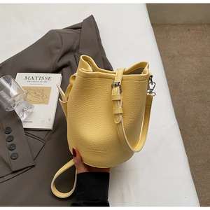 Detail of yellow bucket bag featuring pebbled leather texture and embossed logo