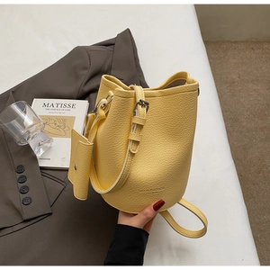 Detail shot of yellow lychee textured bucket bag with small pouch in a fashion setting