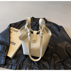Detailed view of beige lychee pattern leather bucket bag with unique handle closure