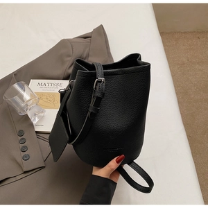 Detail of black lychee grain leather bucket bag with silver buckle and mini pouch