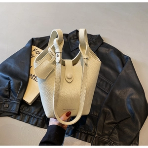 Detailed close-up of cream-white lychee grain leather bucket bag with wrap-around handle
