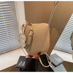 Détail du sac selle blanc cassé en cuir grainé avec un joli pendentif de chien