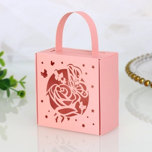Detail of pink laser-cut wedding favor box with butterfly and rose hollow patterns