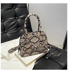 Detail of snakeskin pattern shell bag with metal hardware and adjustable shoulder strap