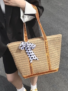 Woven straw tote bag with orange trim and polka dot scarf for summer fashion
