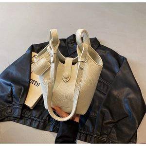 Detail of off-white bucket bag featuring lychee grain texture and brand logo lettering
