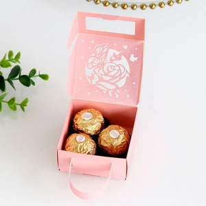 Detail of pink laser-cut butterfly gift box with elegant rose hollow pattern and handle