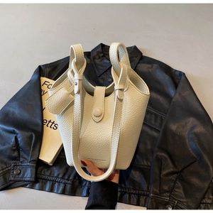 Detail of off-white lychee grain leather bucket bag with clasp and brand logo