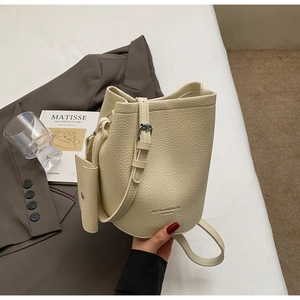 Detail of a creamy white leather bucket bag with an adjustable strap and mini coin purse