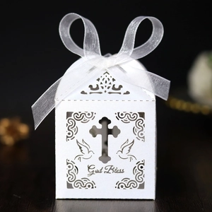 Detail of white laser-cut favor box with God Bless text, cross and dove patterns