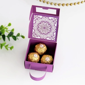 Detalle de caja de dulces morada cortada con láser con elegantes motivos florales y asa