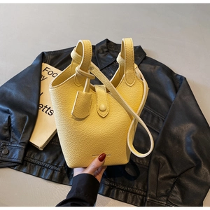 Detail of yellow bucket bag featuring lychee grain leather and secure snap closure