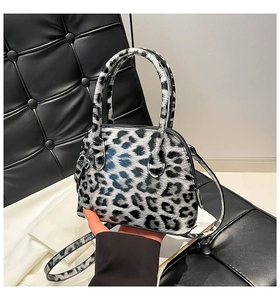 Detail view of the glossy leopard print shell bag with dual handles and shoulder strap