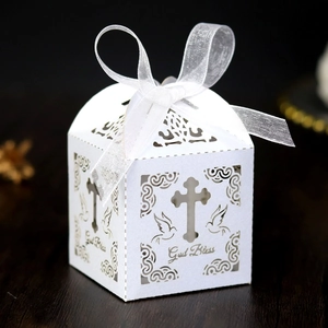 Detail of laser-cut white favor box with God Bless text, cross and dove design