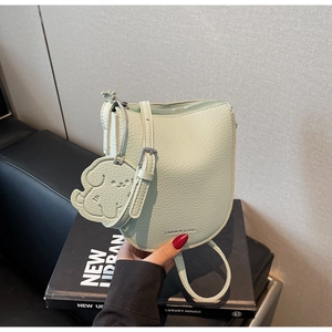 Détail du sac selle vert menthe avec texture grainée et charmant pendentif chien