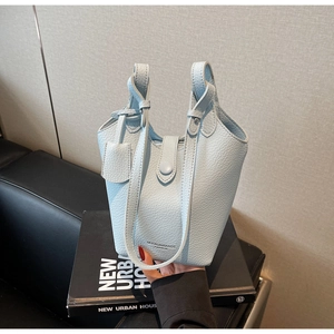 Detail of light blue bucket bag with lychee grain texture and snap button closure