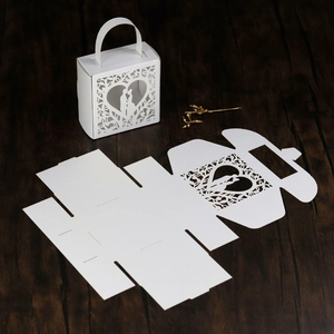 Detail of laser-cut wedding favor box with heart silhouette and foldable paper design