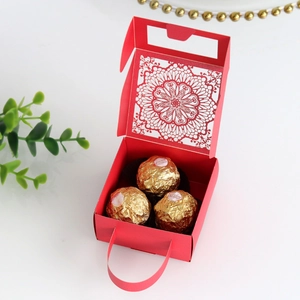 Detalle de caja de dulces roja cortada con láser con patrón floral y asa de cinta