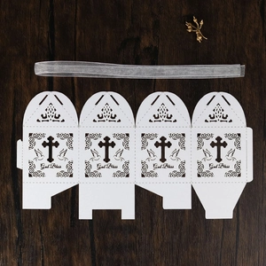 Flat lay of laser-cut 'God Bless' white gift box with hollow cross and white ribbon
