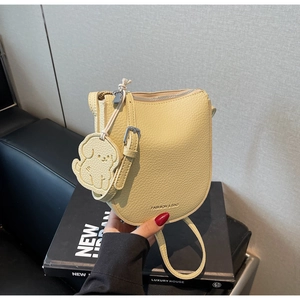 Détail du sac selle en cuir jaune clair à motif litchi avec un charmant chien