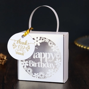 Close-up of laser-cut white cardstock candy box with gold 'Thank You' tag for birthday party