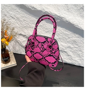 Detail of pink and black snakeskin pattern on a mini dome shell bag with thin strap