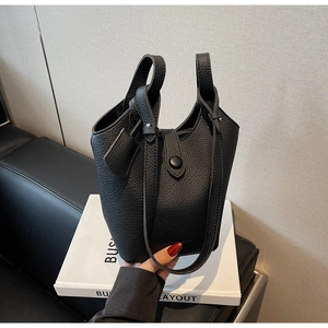 Close-up of black lychee grain leather bucket bag with elegant metal buckle detail