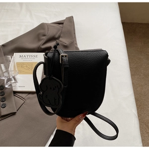 Détail du sac selle en cuir grainé noir avec zip argenté et breloque chien mignonne