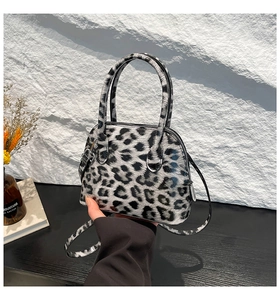 Close-up of leopard print mini shell bag with chain strap and glossy leather finish