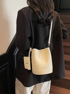 Creamy white pebbled leather bucket bag with shoulder strap and mini coin purse charm