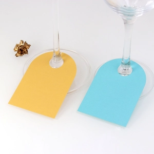 Close-up of pearlized paper wine glass place cards in gold and blue for wedding tables