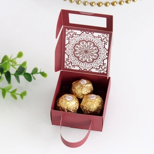 Detalle de la caja de dulces burdeos cortada por láser con patrones florales y un asa