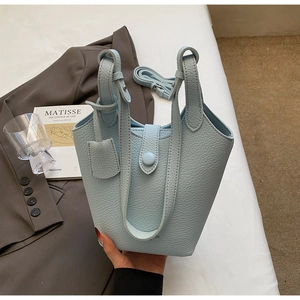 Detail of light blue pebble leather bucket bag showing grain texture and detachable strap