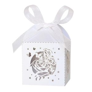 Detail of white laser-cut wedding candy box with rose patterns and a silk ribbon bow