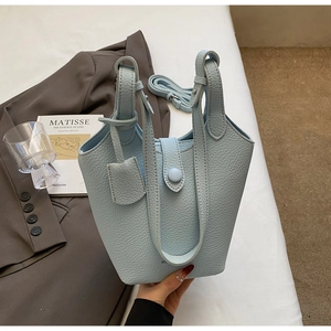 Detail of light blue lychee pattern bucket bag with strap and leather tag decor