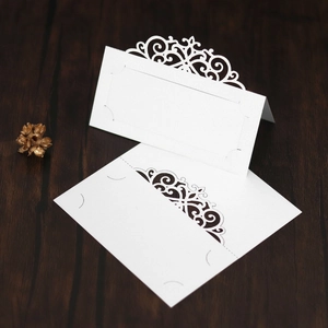 Macro detail of white laser-cut place cards with elegant floral scroll patterns