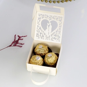 Detail of laser-cut heart pattern with kissing couple on cream wedding candy box