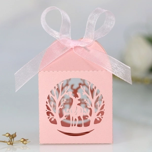 Gros plan sur une boîte cadeau rose découpée au laser avec motif renne et ruban soyeux