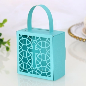 Détail d'une boîte cadeau bleu ciel en papier perlé avec motif croix découpé au laser