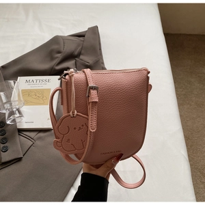Détail du sac selle rose à grain de litchi avec charm chien et bandoulière