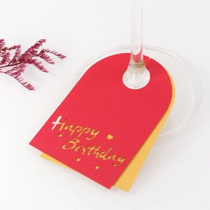 Detalle de tarjetas de copa de vino Happy Birthday en rojo y dorado con letras huecas