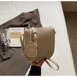 Vue détaillée du sac selle crème en cuir grainé avec une décoration créative de petit chien
