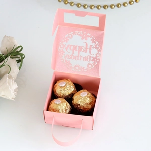 Close-up of pink hollow paper candy box with Happy Birthday cut-out and golden chocolates