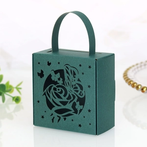 Close-up of laser-cut rose and butterfly patterns on dark green paper wedding candy box