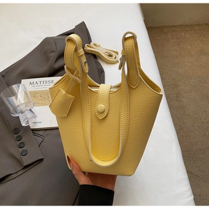 Detail of yellow lychee pattern leather bucket bag with dual handles and long shoulder strap